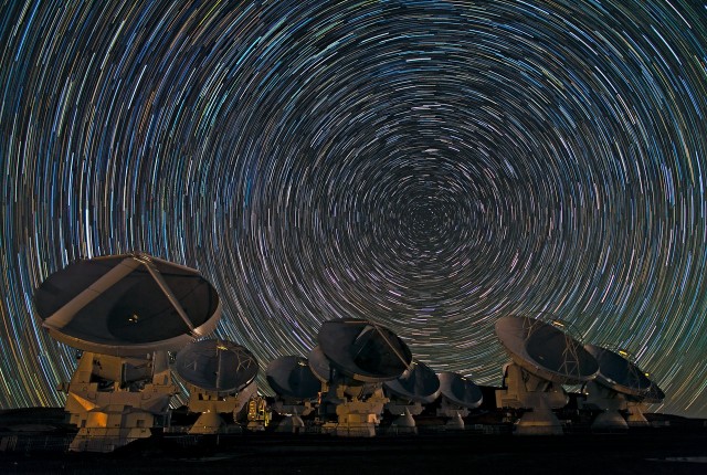 Babak Tafreshi, one of the ESO Photo Ambassadors, has captured the antennas of the Atacama Large Millimeter/submillimeter Array (ALMA) under the southern sky in another breathtaking image. The dramatic whorls of stars in the sky are reminiscent of van Gogh’s Starry Night, or — for science fiction fans — perhaps the view from a spacecraft about to enter hyperspace. In reality, though, they show the rotation of the Earth, revealed by the photograph’s long exposure. In the southern hemisphere, as the Earth turns, the stars appear to move in circles around the south celestial pole, which lies in the dim constellation of Octans (The Octant), between the more famous Southern Cross and the Magellanic Clouds. With a long enough exposure, the stars mark out circular trails as they move. The photograph was taken on the Chajnantor Plateau, at an altitude of 5000 metres in the Chilean Andes. This is the site of the ALMA telescope, whose antennas can be seen in the foreground. ALMA is the most powerful telescope for observing the cool Universe — molecular gas and dust, as well as the relic radiation of the Big Bang. When ALMA construction is complete in 2013, the telescope will have 54 of these 12-metre-diameter antennas, and twelve 7-metre antennas. However, early scientific observations with a partial array already began in 2011. Even though it is not fully constructed, the telescope is already producing outstanding results, outperforming all other telescopes of its kind. Some of the antennas are blurred in the photograph, as the telescope was in operation and moving during the shot. ALMA, an international astronomy facility, is a partnership of Europe, North America and East Asia in cooperation with the Republic of Chile. ALMA construction and operations are led on behalf of Europe by ESO, on behalf of North America by the National Radio Astronomy Observatory (NRAO), and on behalf of East Asia by the National Astronomical Observatory of Japan (NAOJ). The Joint ALMA
