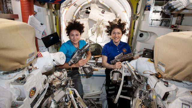Jessica Meir (izquierda) y Christina Koch (derecha) en la cámara Quest de la Estación Espacial Internacional preparándose para su inminente actividad extravehicular. 18 de octubre de 2019. Fuente: [1st all-female spacewalk].